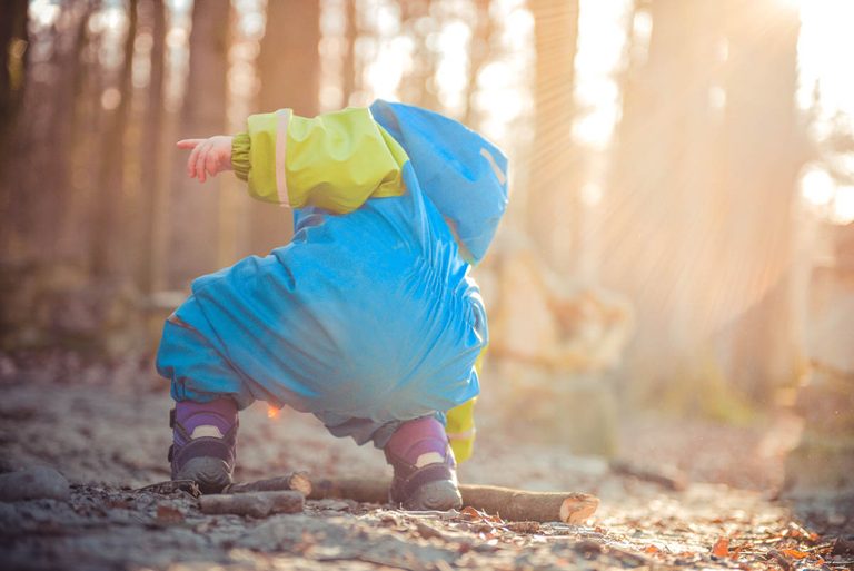 Kind im Matschkleidung im Wald 