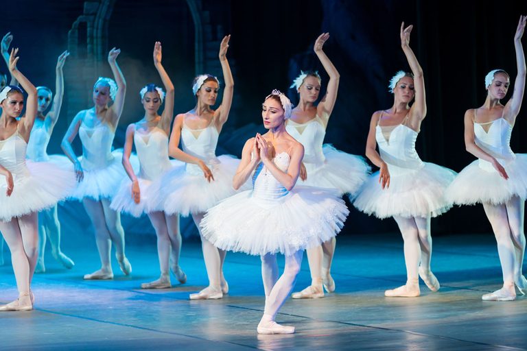 Ballerinas in weißen Kleidern tanzen auf einer Bühne 