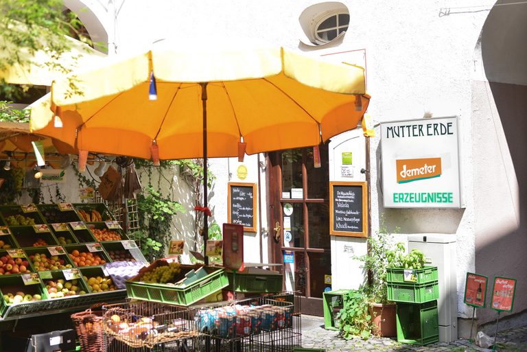 Gemüse und Sonnenschirm vor dem Laden